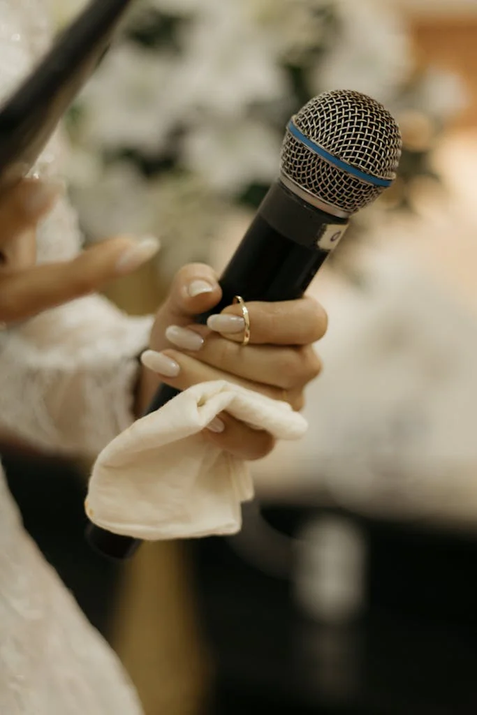 Bride holding a microphone during her wedding speech, symbolizing love and celebration.